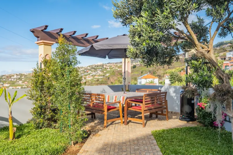 Pergola s dřevěným posezením a slunečníkem v zahradě